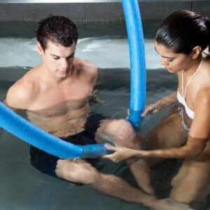 person working with physical therapist in aquatic therapy